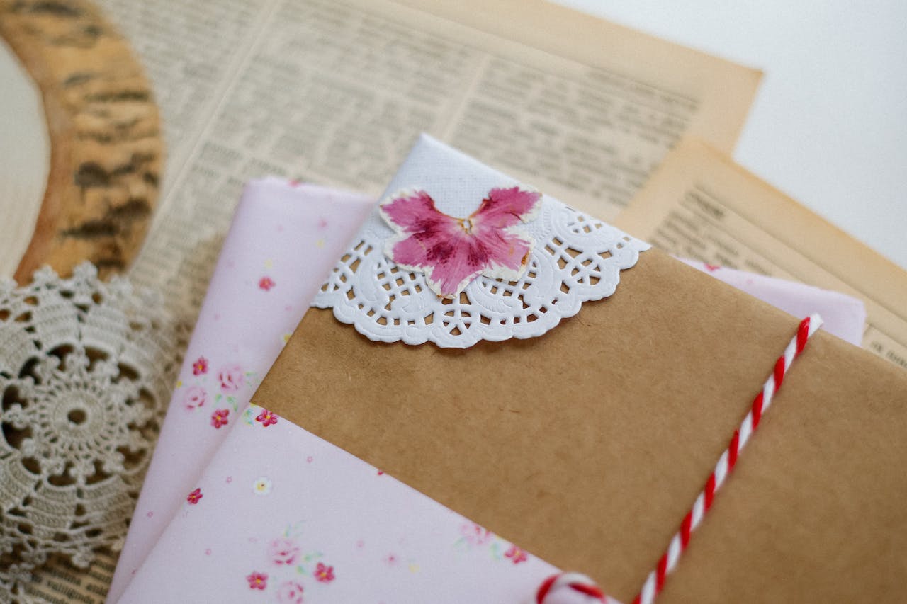A beautifully wrapped handmade gift with floral accents and a decorative paper doily on antique paper.