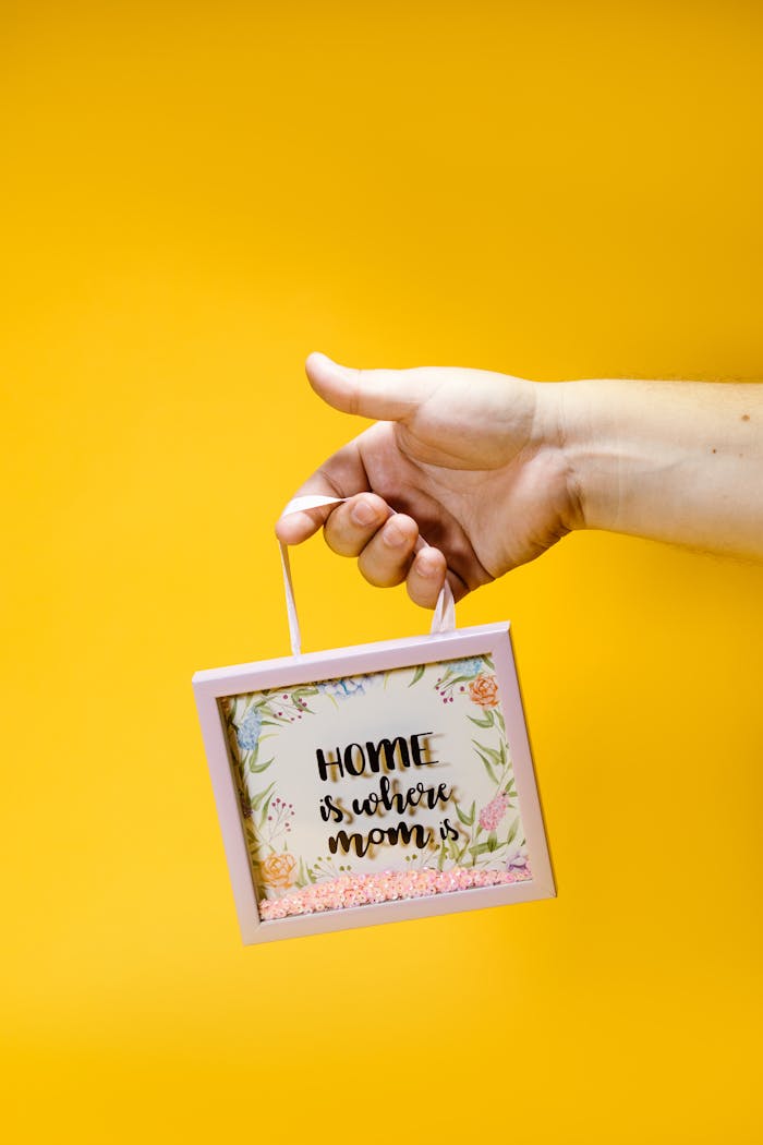 A hand holding a shadow box gift with floral design and 